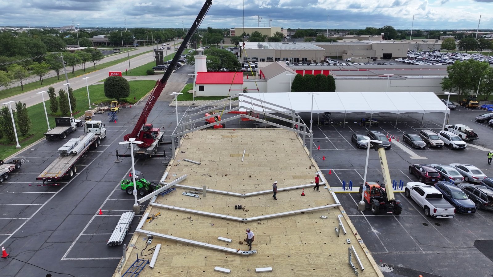 Crane installing tent structure on top of large raised deck platform