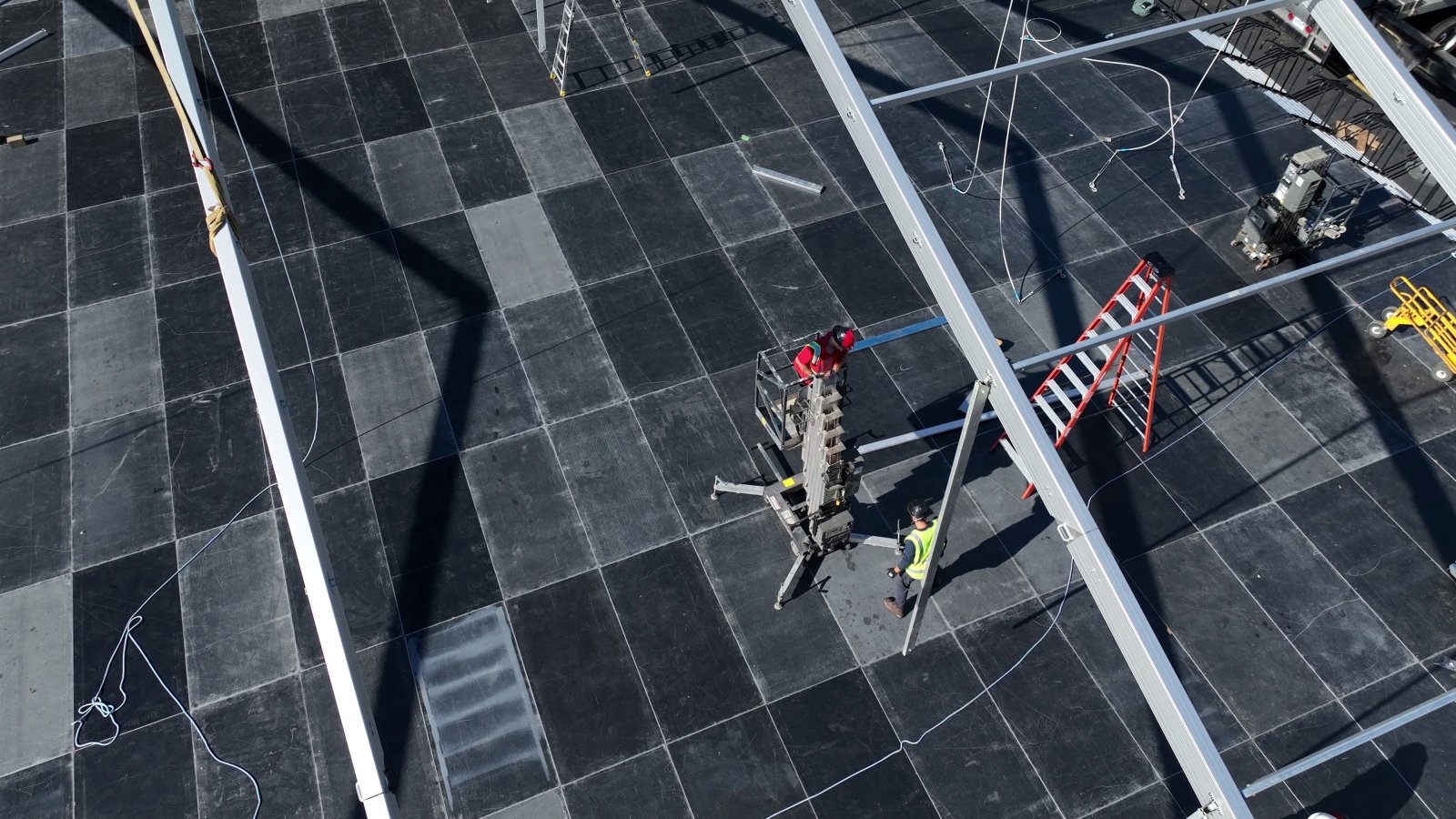 Workers installing tent structure on top of raised leveled deck platform