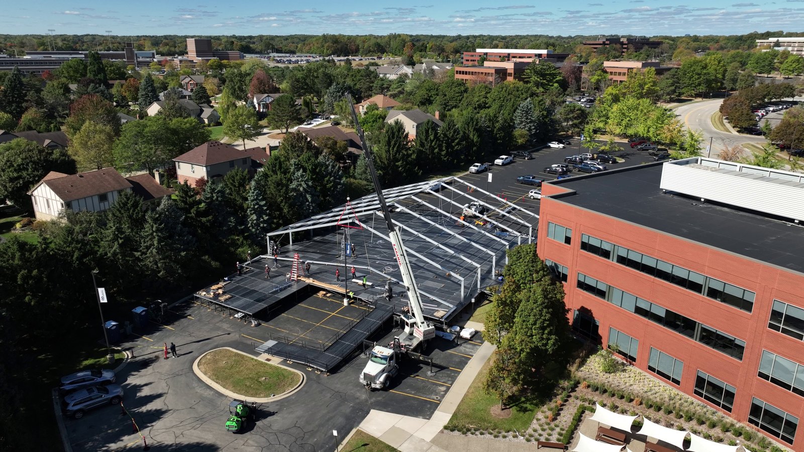 Wide aerial view of raised deck with crane and tent structure framing being installed