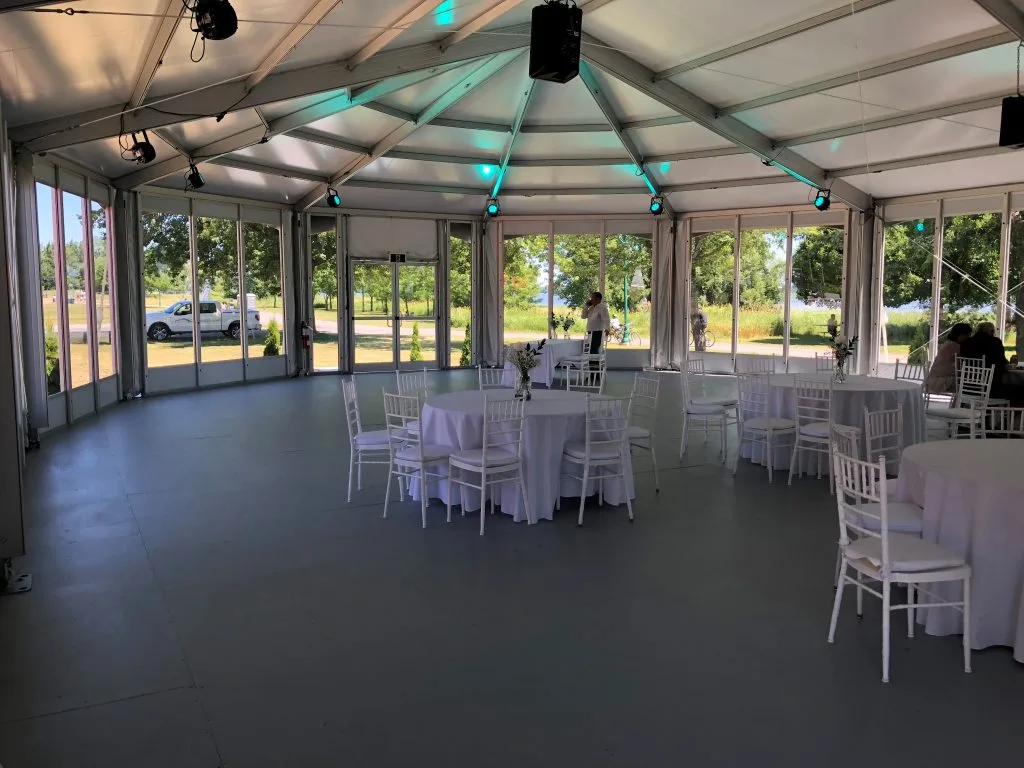 Interior of a glass wall structure tent set with banquet rounds and Chiavari chairs